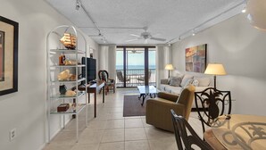A living room with a view of the sea, a balcony, and a dining area.