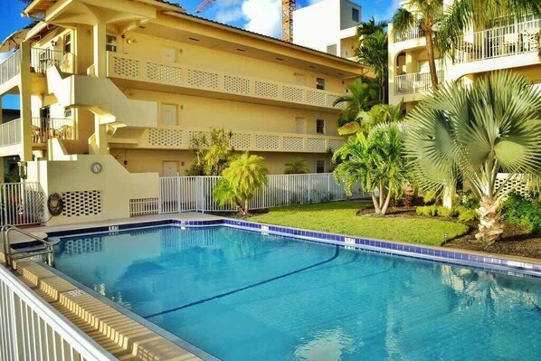 Una piscina rodeada de una valla, con un edificio al fondo.