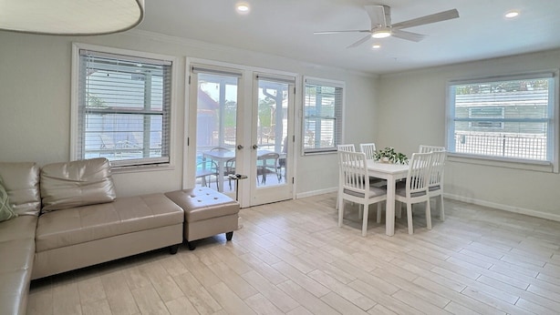 A spacious room with a white ceiling fan, a beige sofa, a dining table with chairs, and large windows with blinds. - Small and Quiet Lakefront Resort on Siesta Key W/ Heated Pool and Kayaks (Siesta Key)