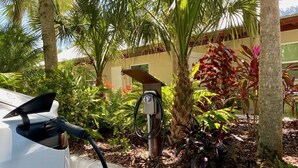 A car charging at a station in a landscaped area with palm trees and various plants. - Small and Quiet Lakefront Resort on Siesta Key W/ Heated Pool and Kayaks (Siesta Key)