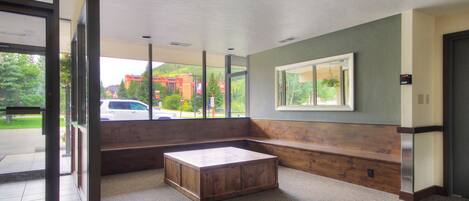 A hotel lobby with a large bench, a reception desk, and a view of the outside.