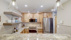 Una cocina moderna con armarios de madera, refrigerador de acero inoxidable y encimera de mármol.