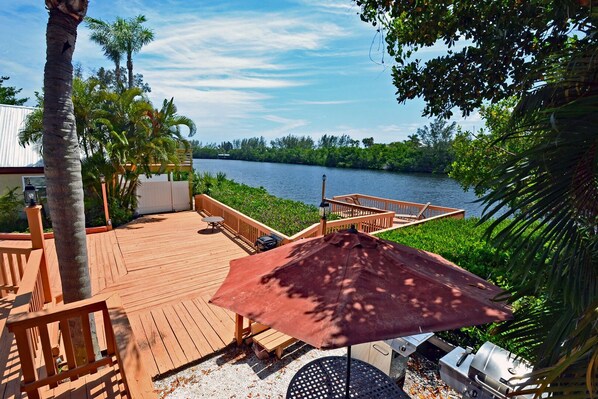 A wooden deck with a table and chairs, overlooking a body of water.