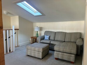 A living room with a sectional sofa, ottoman, and a lamp on a side table. - 6 bdrm home W/Beach & Bay Access (Cape San Blas)
