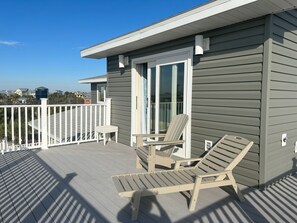 Une terrasse dotée de deux chaises longues et d’une petite table, offrant une vue sur un quartier résidentiel.