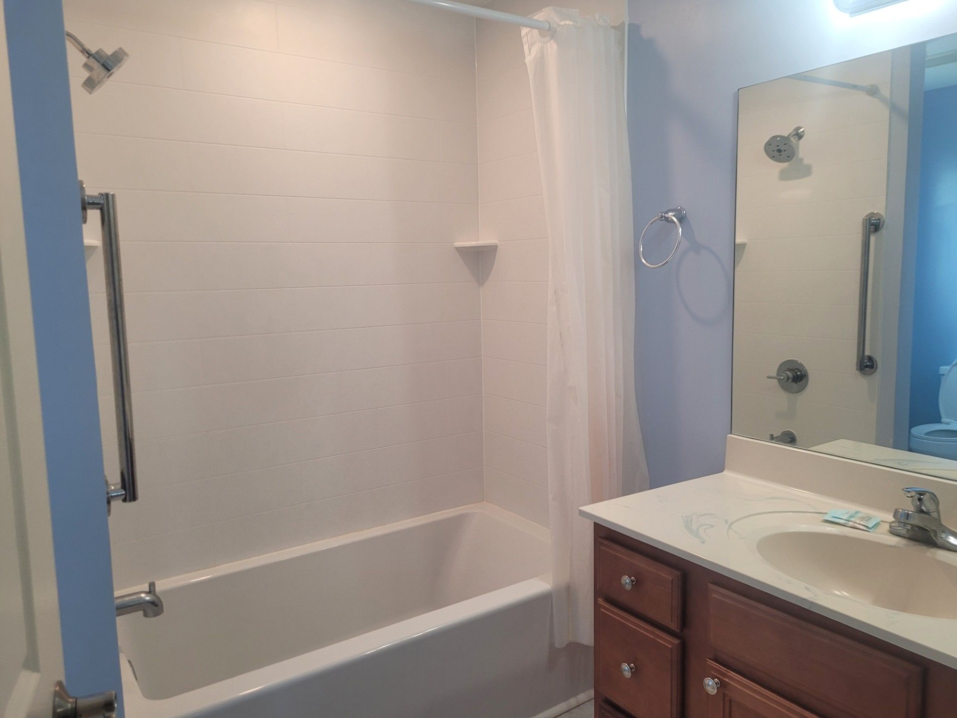 A bathroom with a bathtub, a sink, a mirror, and a shower curtain.