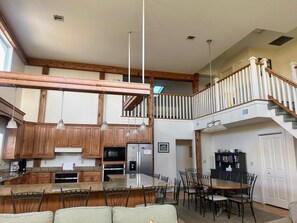 A spacious kitchen with wooden cabinets, a granite countertop, and a dining area with a wooden table and chairs. - 6 bdrm home W/Beach & Bay Access (Cape San Blas)