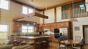 A spacious kitchen with wooden cabinets, a large island with bar stools, and a dining area with a table and chairs.