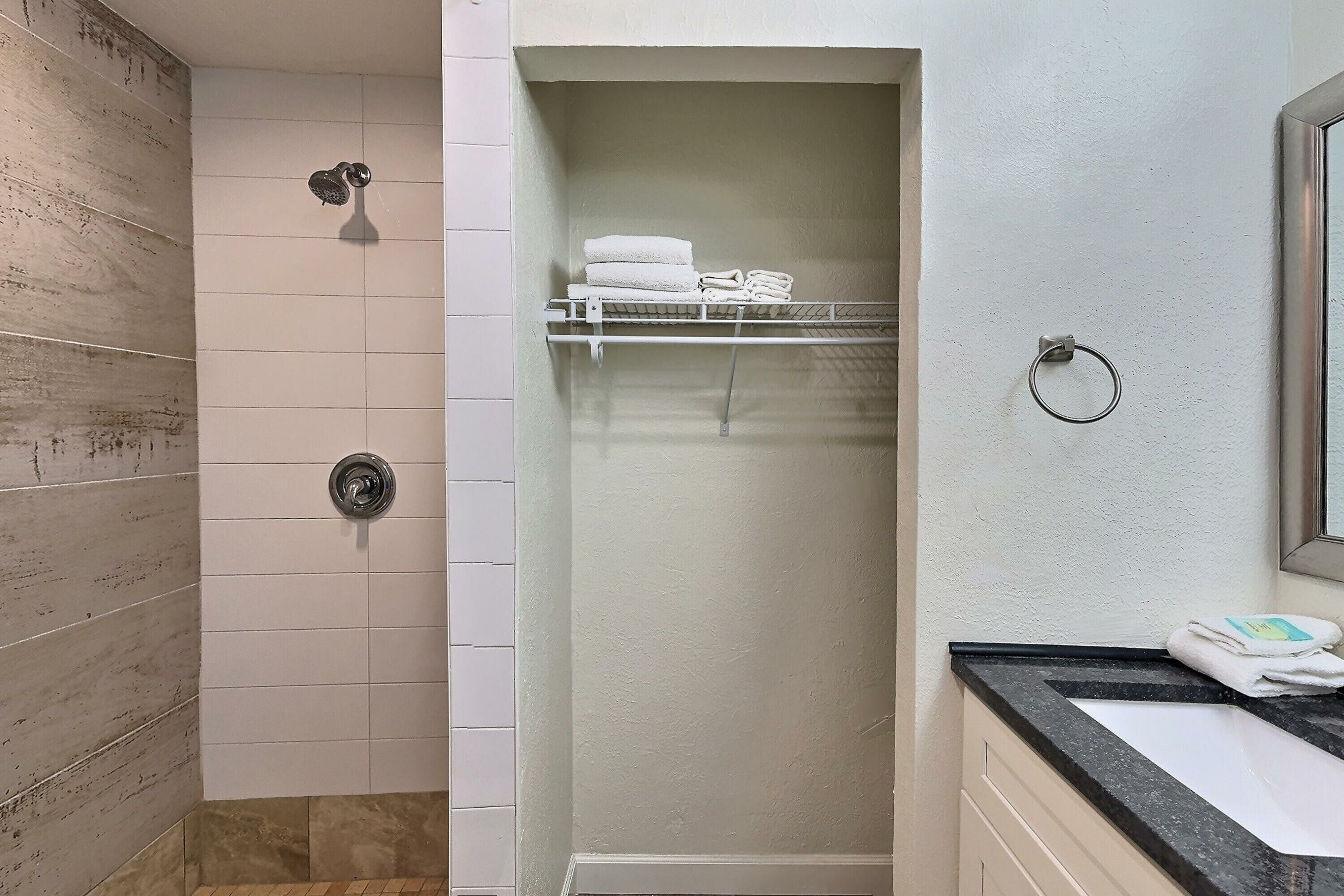 A bathroom with a shower, a towel rack, and a sink.