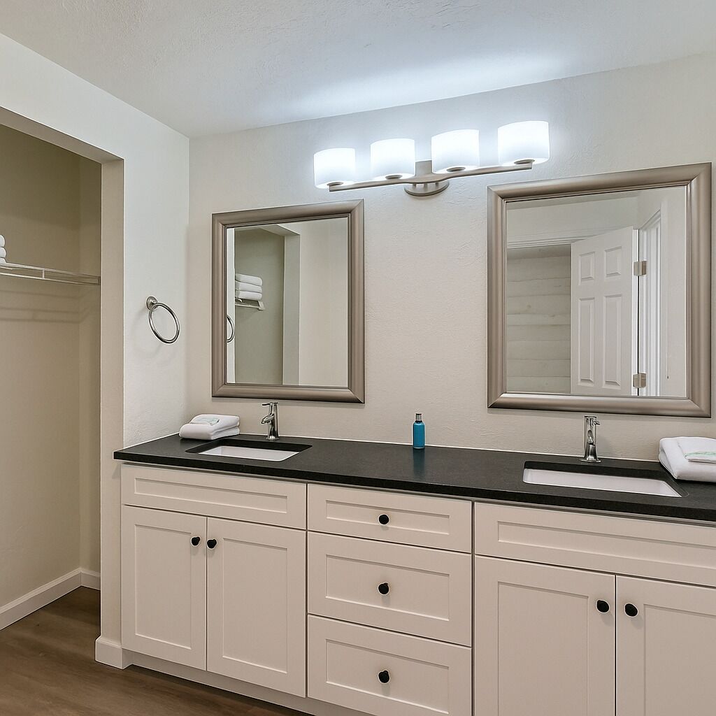 Une salle de bain dotée d’un meuble-lavabo double, de deux grands miroirs, d’un porte-serviettes et d’un espace coiffeuse éclairé.