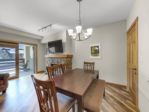 A dining area with a wooden table and chairs, a television mounted above the table, a chandelier, and a fireplace. - Amazing Center Village Unit, Extra Sleeping Area, Walk to American Eagle - PP3 (Copper Mountain)