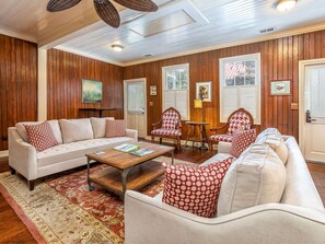 A living room with a beige sofa, matching armchairs, a wooden coffee table, and a patterned rug.