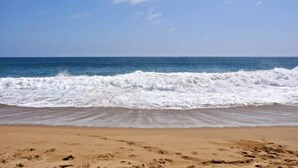Platja amb onades que arriben a la riba sota un cel serè.