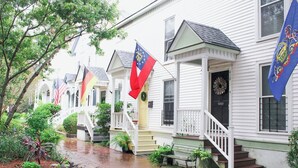 A row of white houses with front porches, each with a flag.