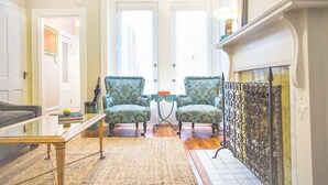 A living room with a sofa, two armchairs, a coffee table, and a fireplace. - Well Appointed Row Home w/ King, Across from Forsyth Park by Lucky Savannah (Savannah)