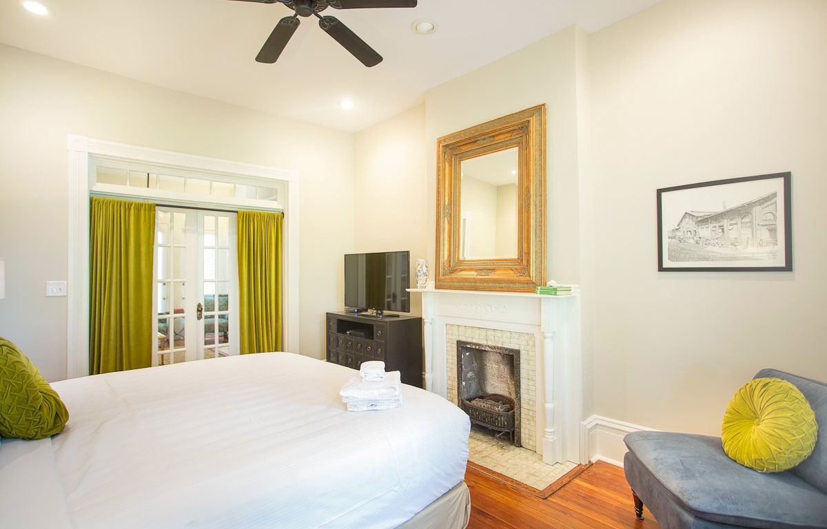 A bedroom with a bed, a television, a fireplace, and a chair.
