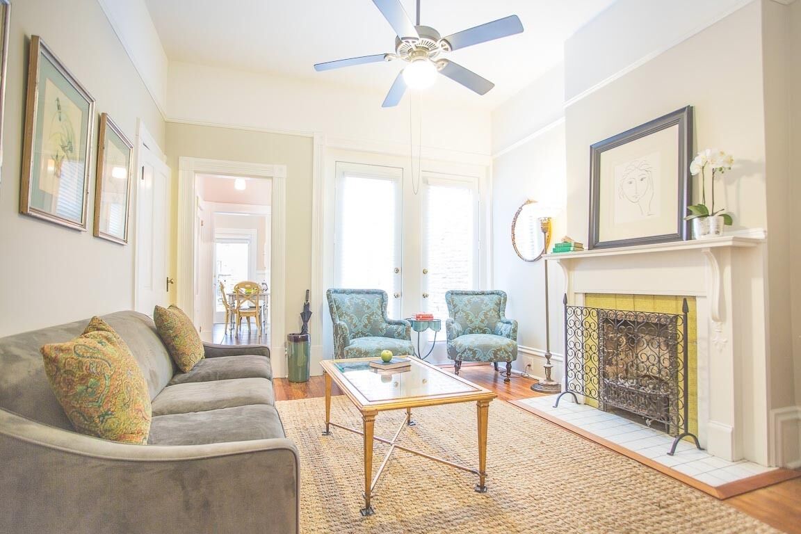 A living room with a sofa, armchairs, a coffee table, a fireplace, and framed artwork on the walls.