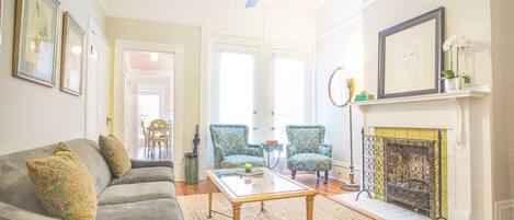 A living room with a sofa, armchairs, a coffee table, a fireplace, and framed artwork on the walls.