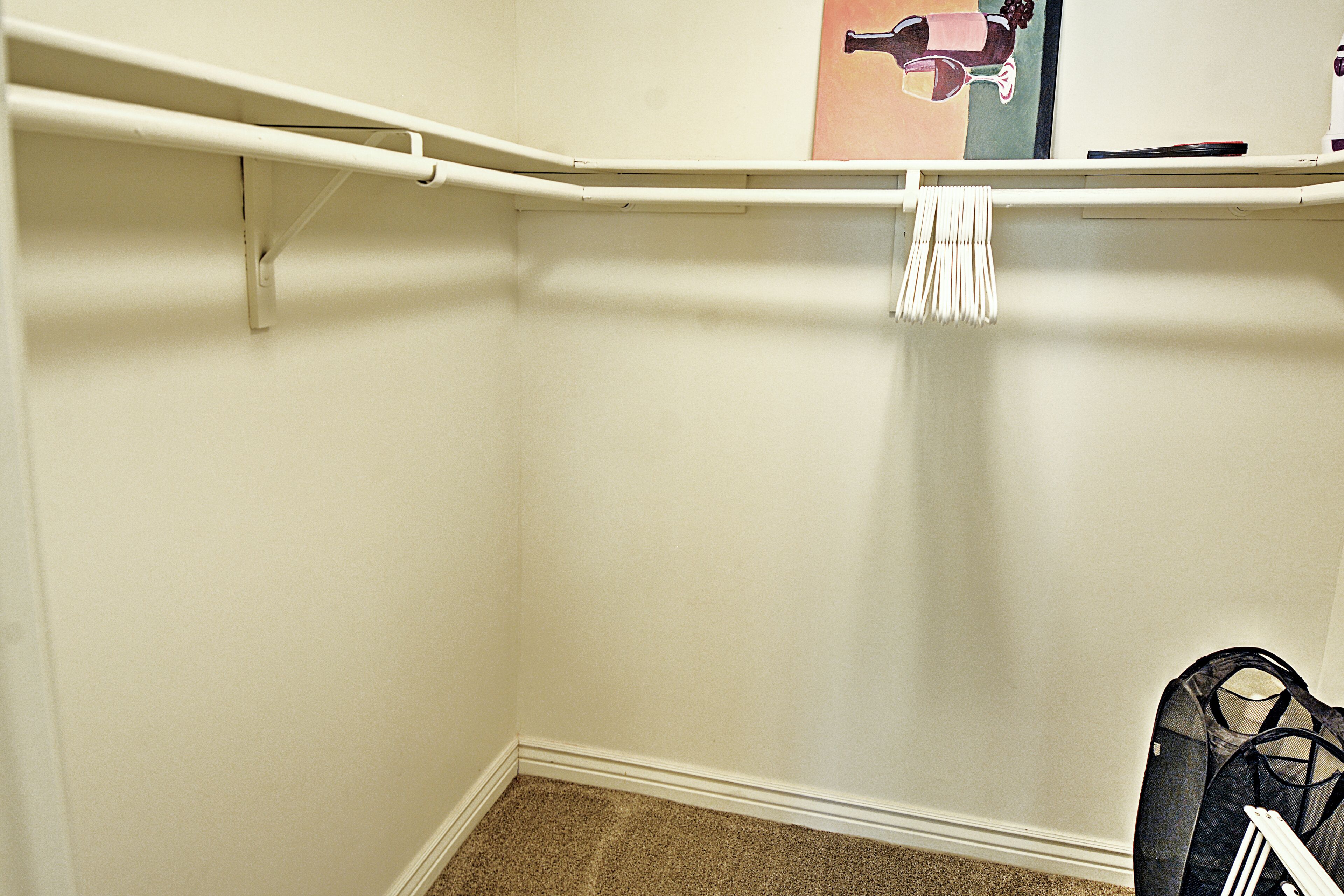 Un coin de pièce avec un mur blanc, une plinthe blanche et un sol recouvert de moquette.