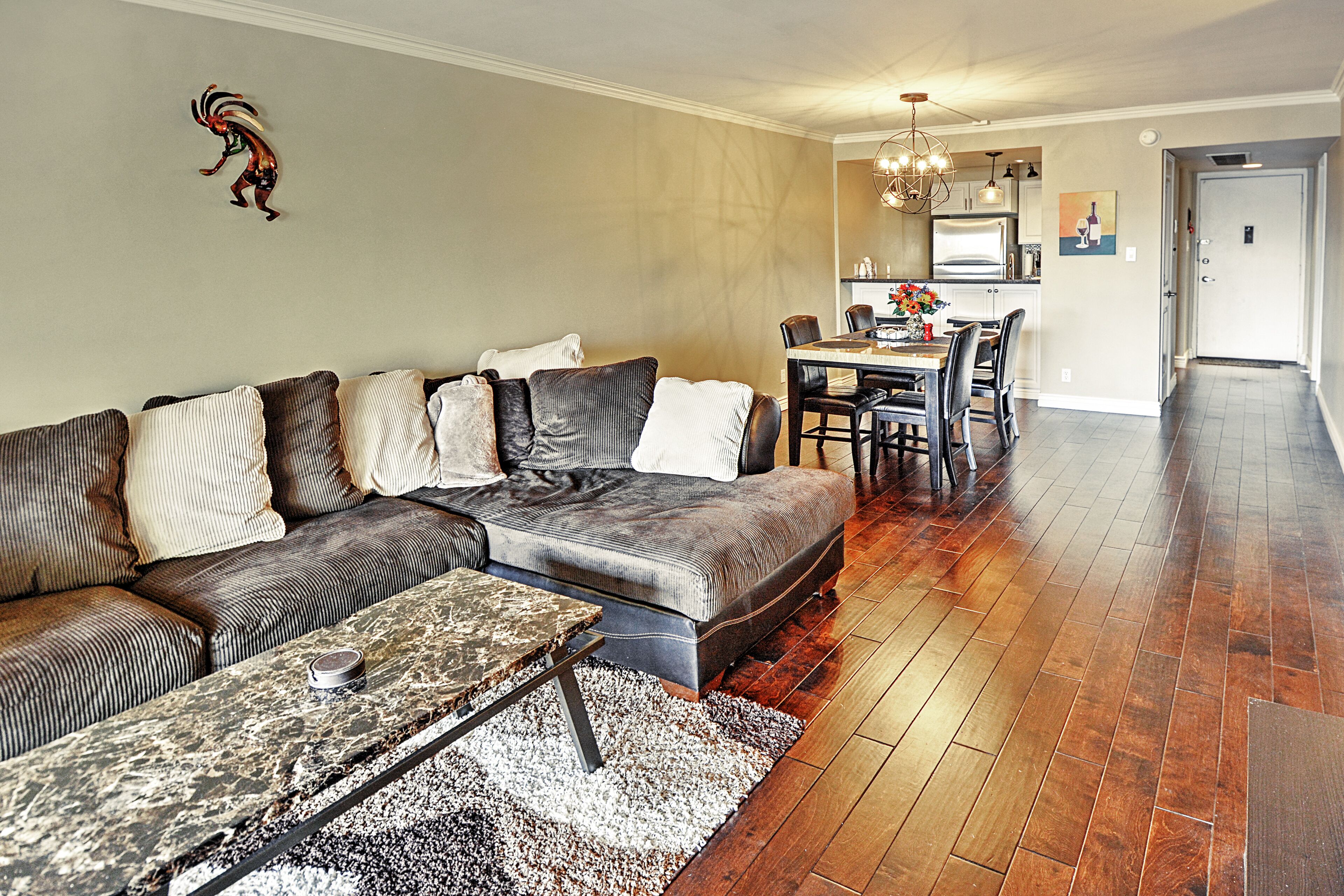 A living room with a sectional sofa, a coffee table, and a dining area with a table and chairs.