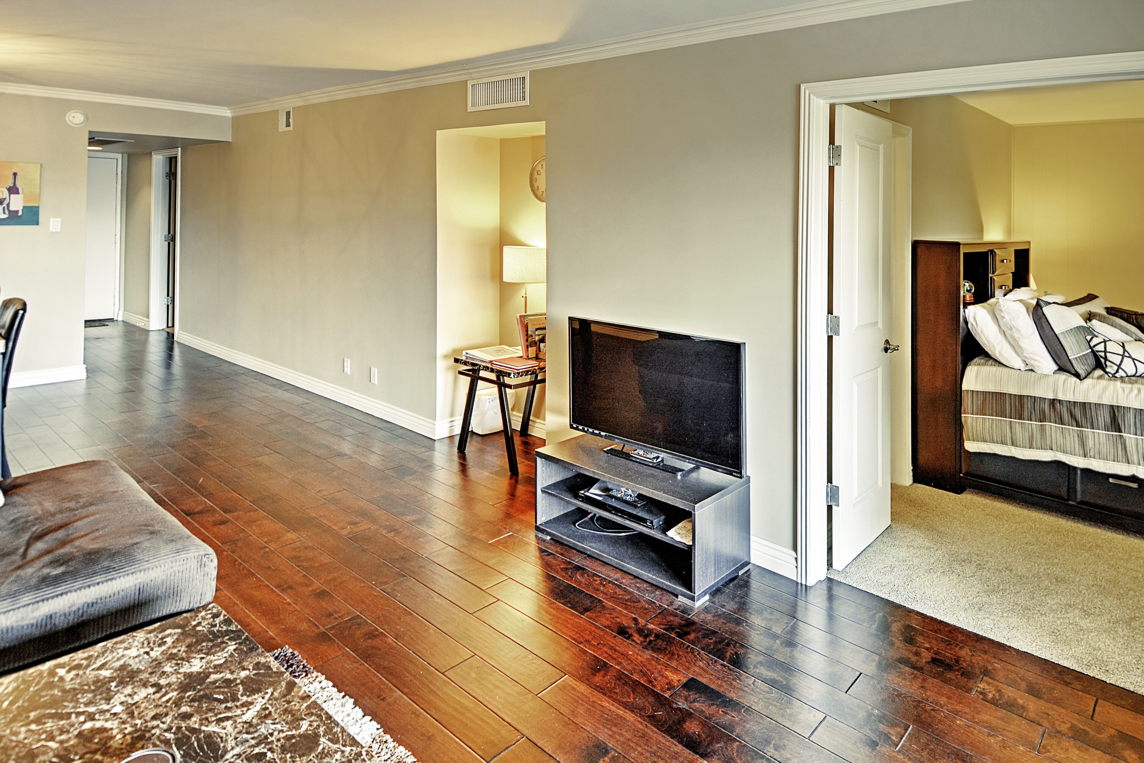 A spacious living room with hardwood flooring, a flat-screen TV, and a comfortable seating area.