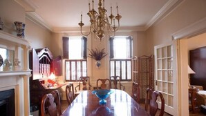 Ein Esszimmer mit einem großen Holztisch, Stühlen, einer Kandelaber und einem Kamin.