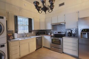 A kitchen with white cabinets, a stainless steel refrigerator, a microwave, an oven, and a dishwasher.