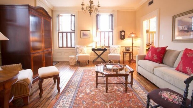 Ein traditionelles Wohnzimmer mit einer großen Holzkabine, einem Sofa mit roten Kissen, einem gemusterten Teppich und einer Chandelier.