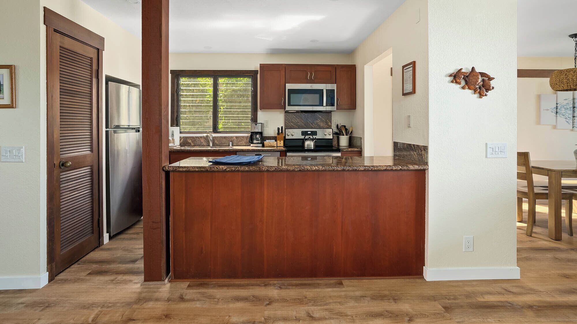 Une cuisine moderne avec des meubles en bois, un réfrigérateur en acier inoxydable, un four à micro-ondes et une cuisinière à gaz.
