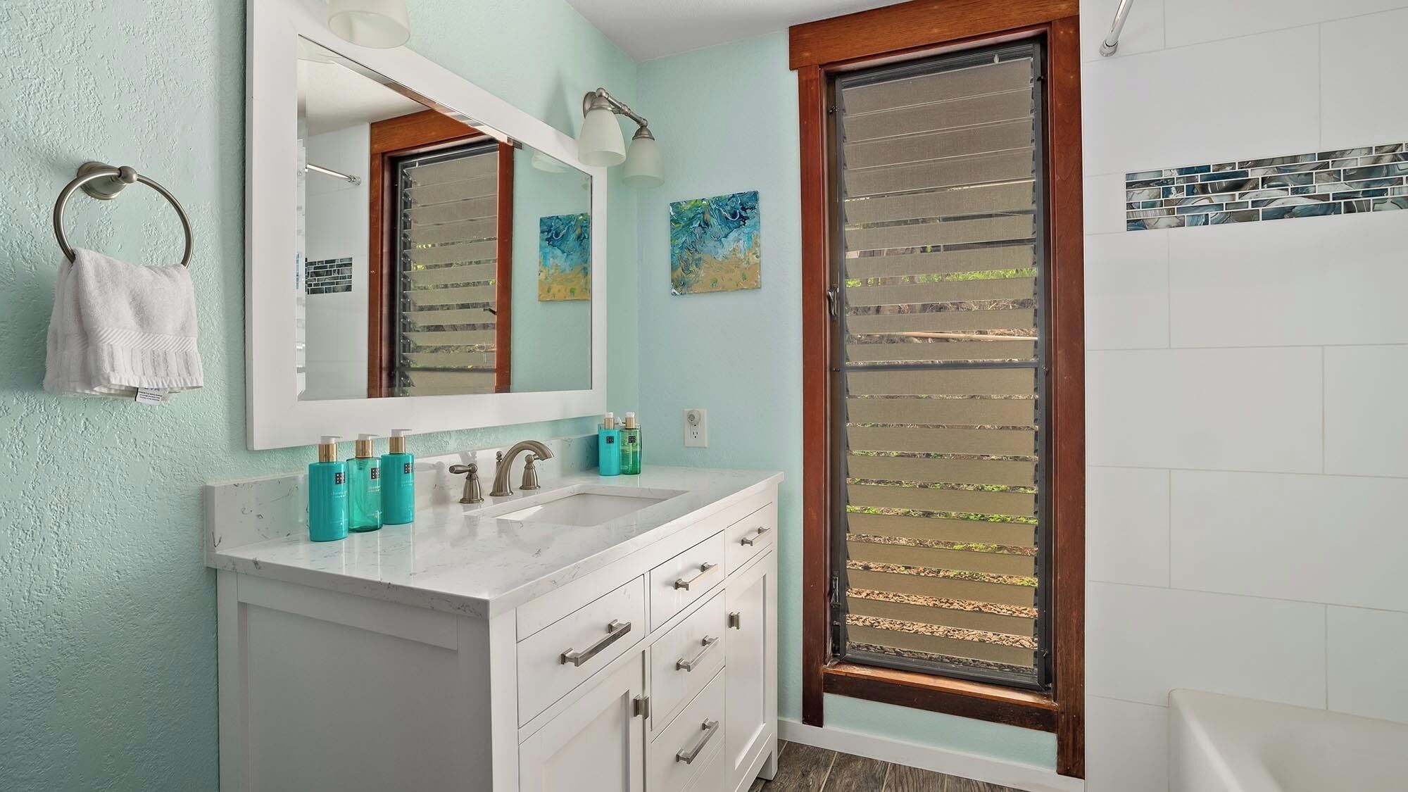 A bathroom with a white vanity, a large mirror, and a shower with a glass door.