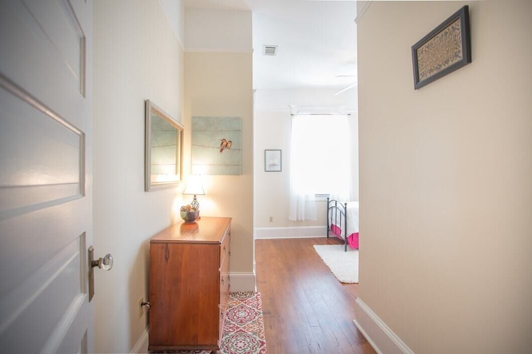 Un couloir avec un meuble en bois, une lampe et un tapis.