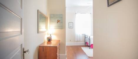 Un couloir avec un meuble en bois, une lampe et un tapis.