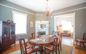 Une salle à manger avec une table ronde, des chaises, un lustre et une cheminée.