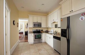 A kitchen with white cabinets, stainless steel appliances, and a tiled floor. - Tasteful Two Bedroom on Warren Square with Parking by Lucky Savannah (Savannah)