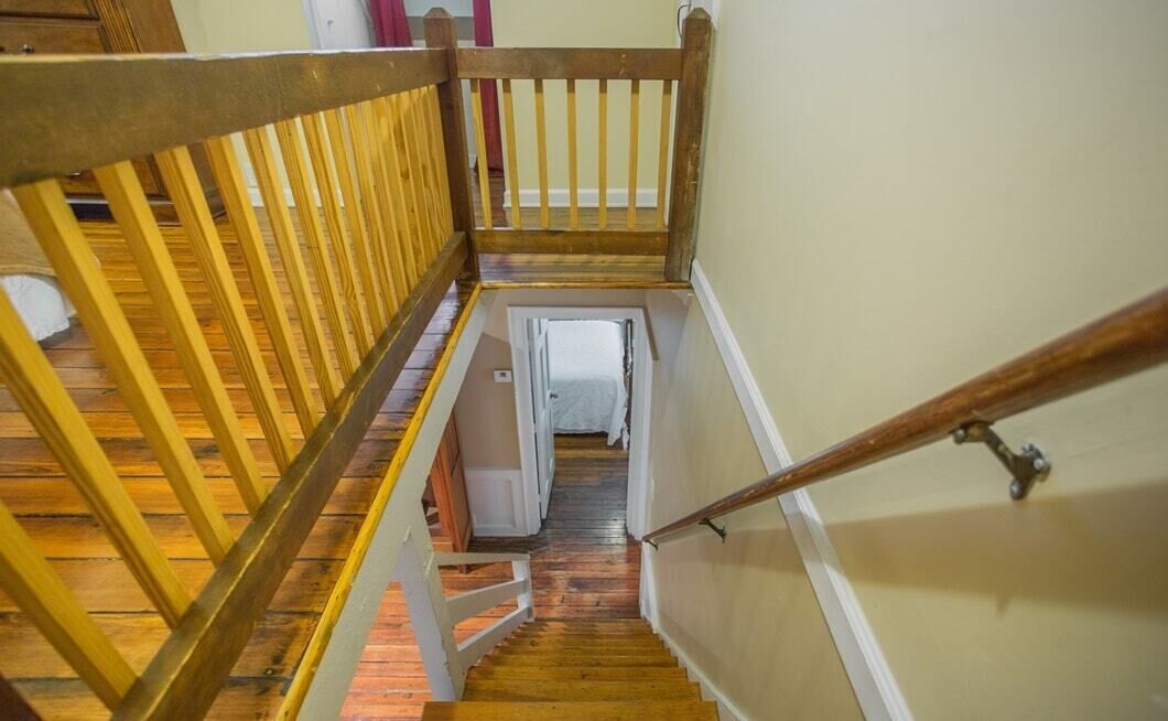 A wooden staircase with a handrail leading to a door at the bottom.