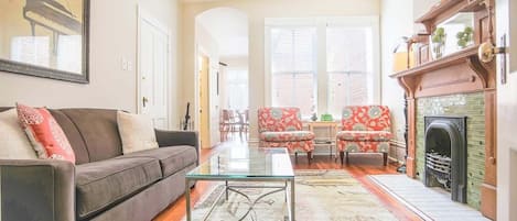 A living room with a sofa, chairs, a glass coffee table, and a fireplace.