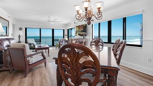A spacious dining area with a large table and ornate chairs, overlooking a scenic ocean view. - Luxury, direct oceanfront 2/2, top-floor corner with wrap-around balcony and heated pool (New Smyrna Beach)