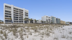 Ein Strandhotel mit mehreren Etagen, Balkonen und Palmen.