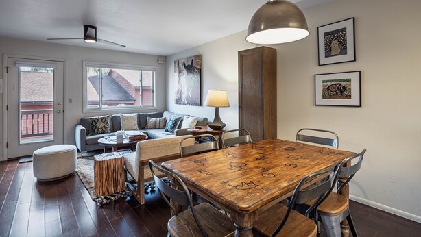 A dining area with a wooden table and chairs, a sofa, a lamp, and artwork on the walls. - Pitchfork 456: Town of Jackson- Renovated- Walk to Town Square (Jackson)