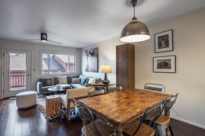 Ein Essbereich mit Holztisch und -stühlen, einer Couch, einer Lampe und Bildern an den Wänden.