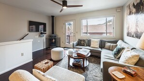 A living room with a sofa, ottoman, coffee table, fireplace, and a ceiling fan. - Pitchfork 456: Town of Jackson- Renovated- Walk to Town Square (Jackson)