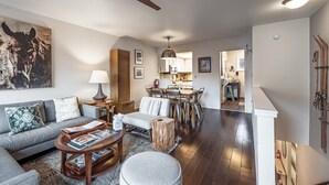 A living room with a sofa, coffee table, and a dining area with chairs and a table. - Pitchfork 456: Town of Jackson- Renovated- Walk to Town Square (Jackson)