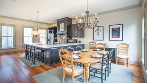 A spacious kitchen with a large island, dark cabinetry, and a chandelier.