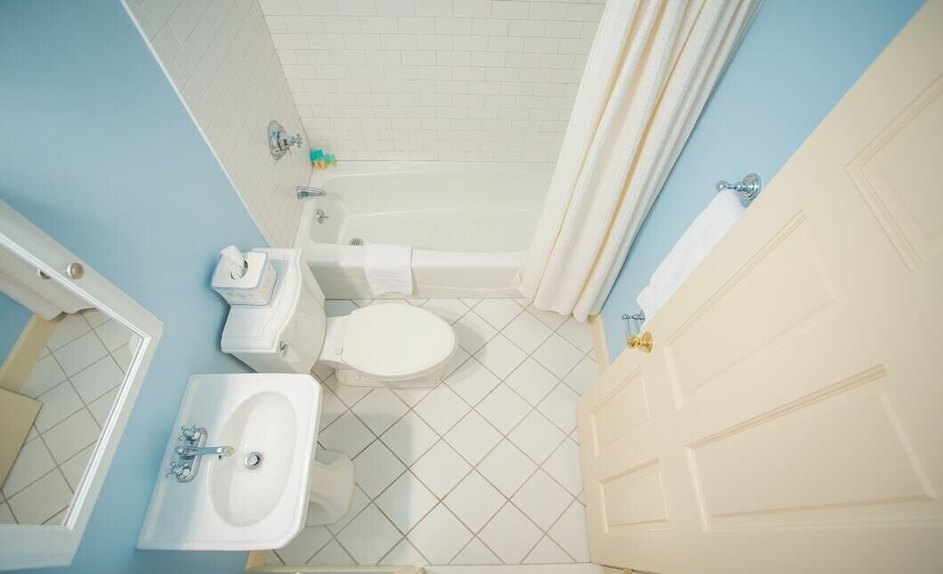 A bathroom with a bathtub, toilet, sink, and a door.