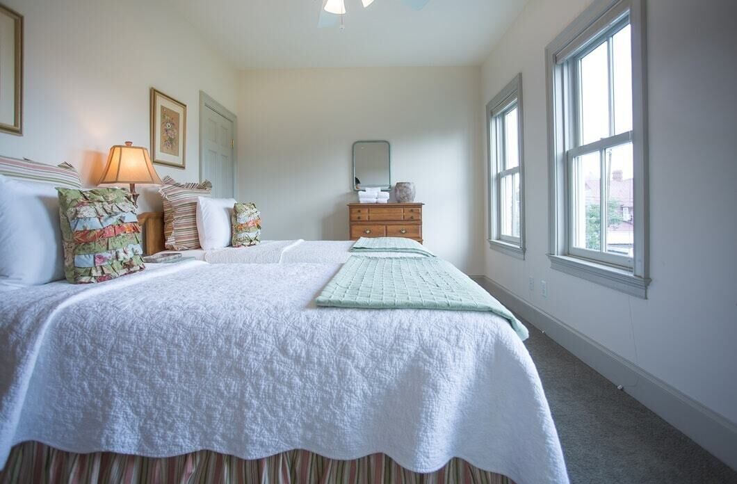 A bedroom with a large bed, a dresser, a mirror, and a window.