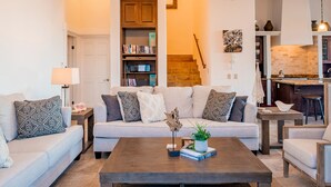 A living room with a sofa, coffee table, and bookshelves. - Pedregal Walk to Beach/Town Villa w/ Ocean, Bay & Marina Views, Pool & Hot Tub (Cabo San Lucas)