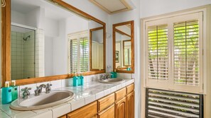 Un baño con dos lavamanos, armarios de madera y un espejo grande.
