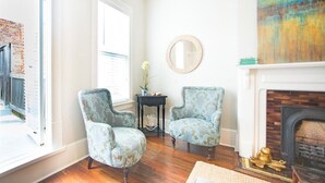 A room with two upholstered armchairs, a small side table, a mirror, and a fireplace.