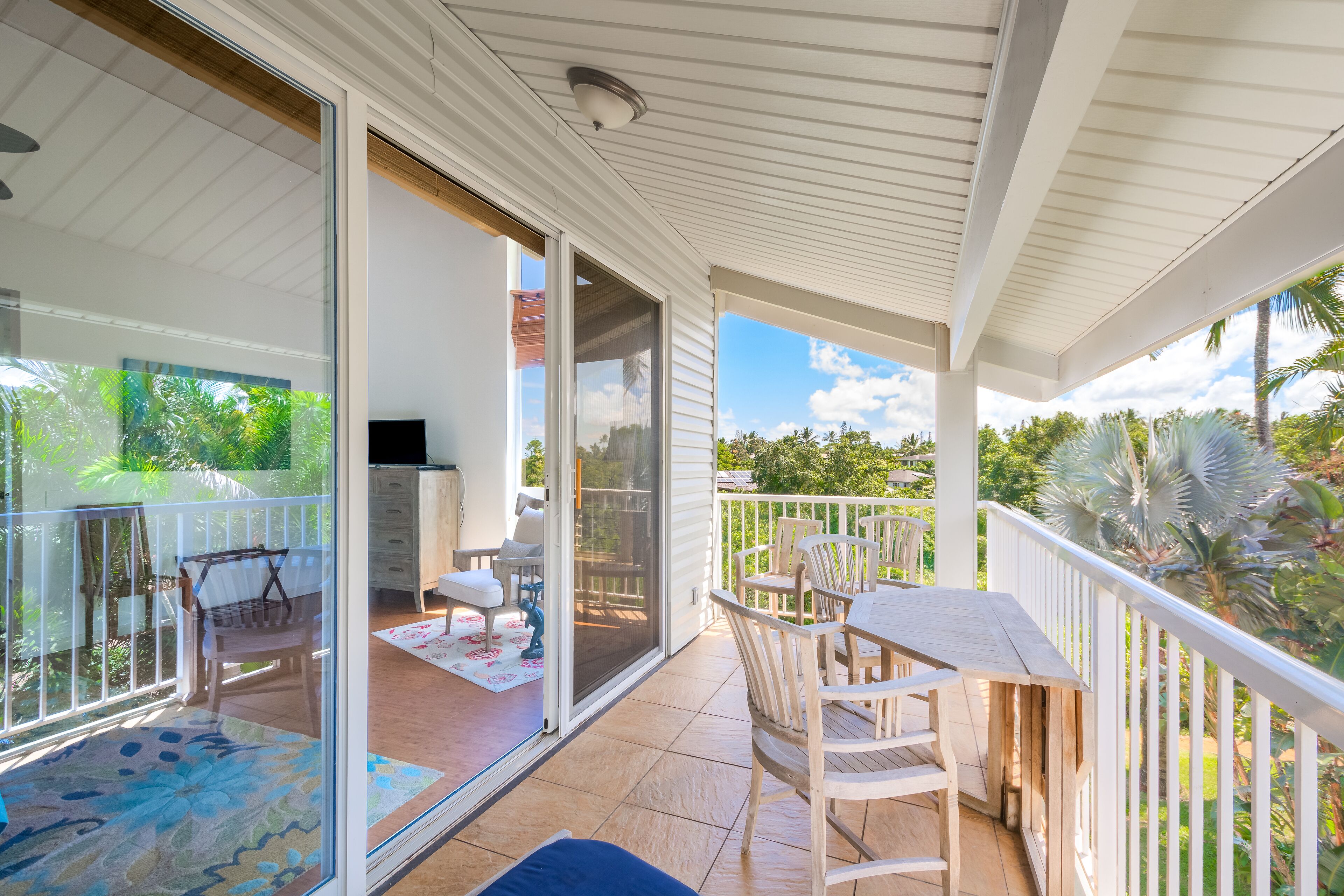A covered balcony with a sliding glass door leading to a patio area.