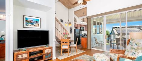 A spacious living room with a large flat-screen TV, wooden entertainment unit, and comfortable seating.